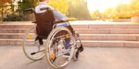 A man helps children in wheelchairs